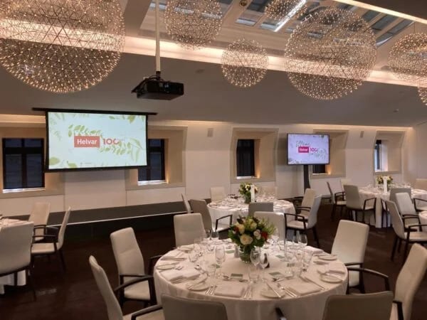 Round dinner tables with florals and screens set for a company centenary dinner