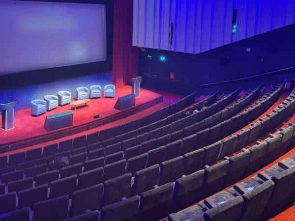 Cinema-style auditorium set for a large corporate conference under blue lighting