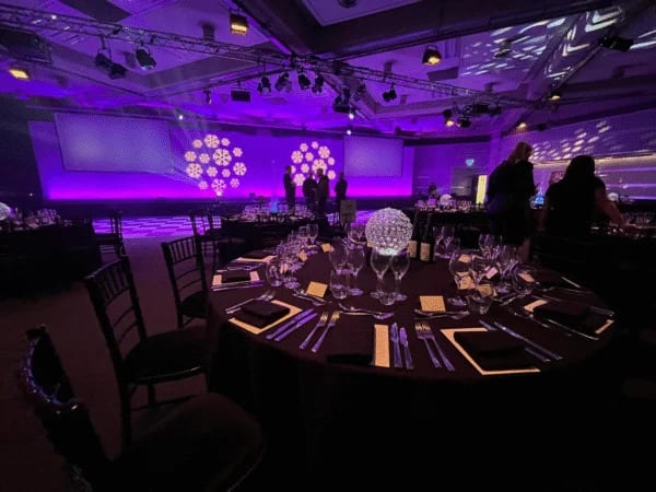 Elegant round dinner table set under decorative snowflake lighting at a private dining event