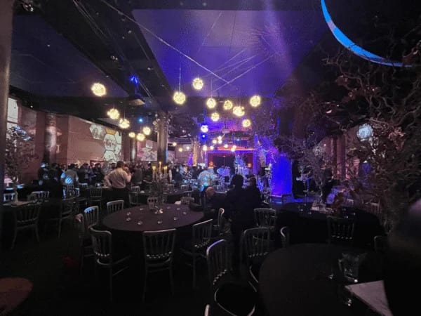 Atmospheric themed event with round dining tables, decorative lighting and a live stage